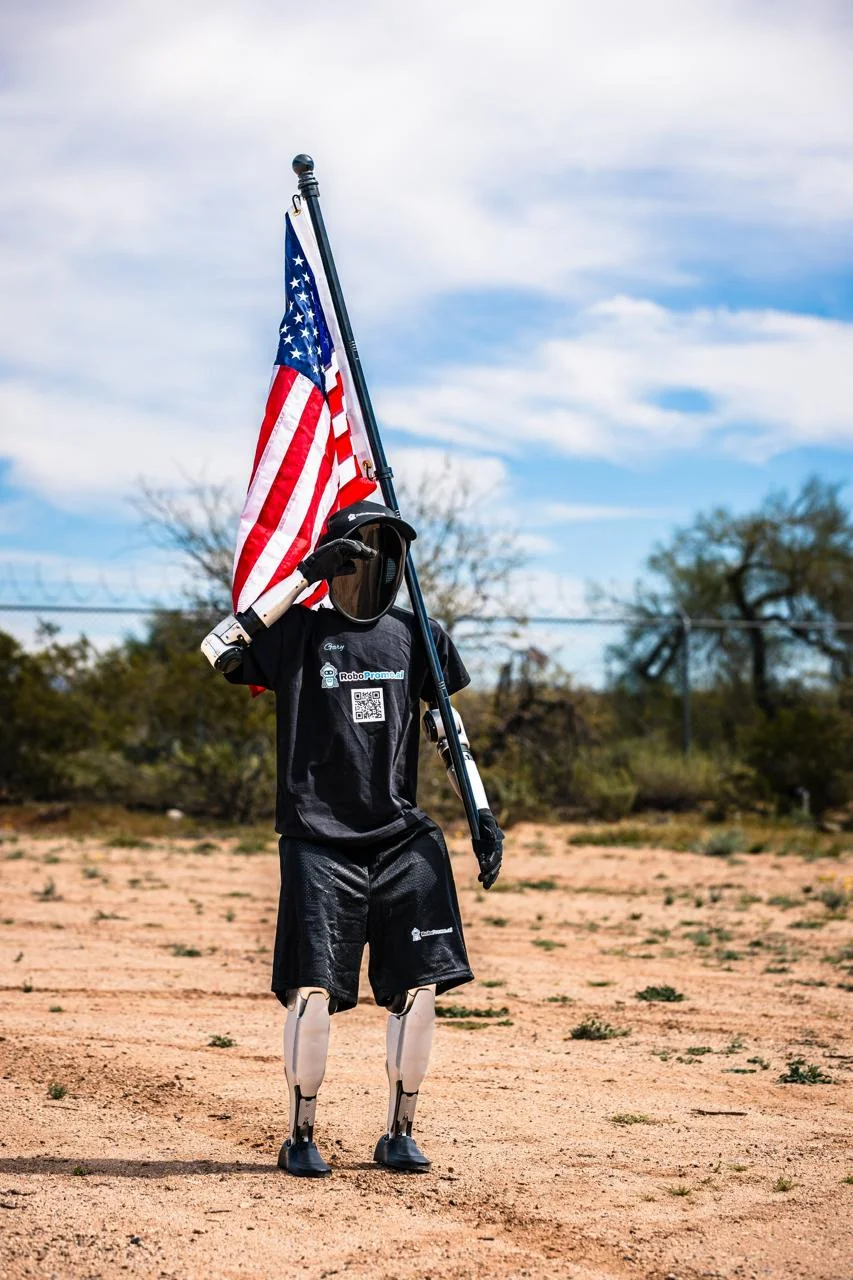Gary, a Unitree G1 humanoid robot holding an American flag outdoors